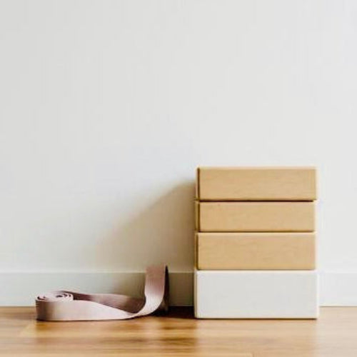 Three stacked boxes of different sizes on a wooden floor against a white wall.